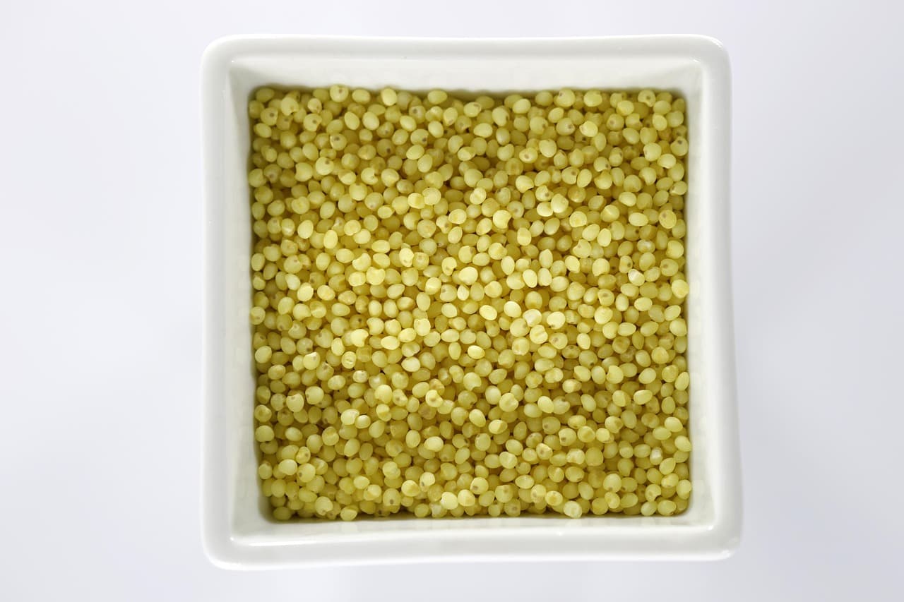 Little millet grains, small round golden seeds, in a white bowl
